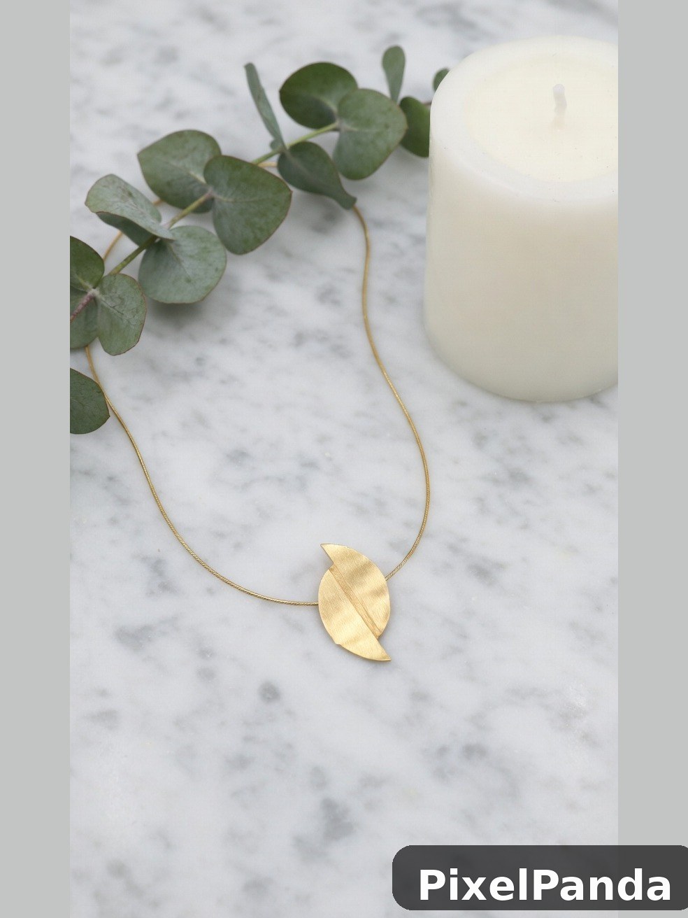 Gold leaf pendant necklace with eucalyptus on marble