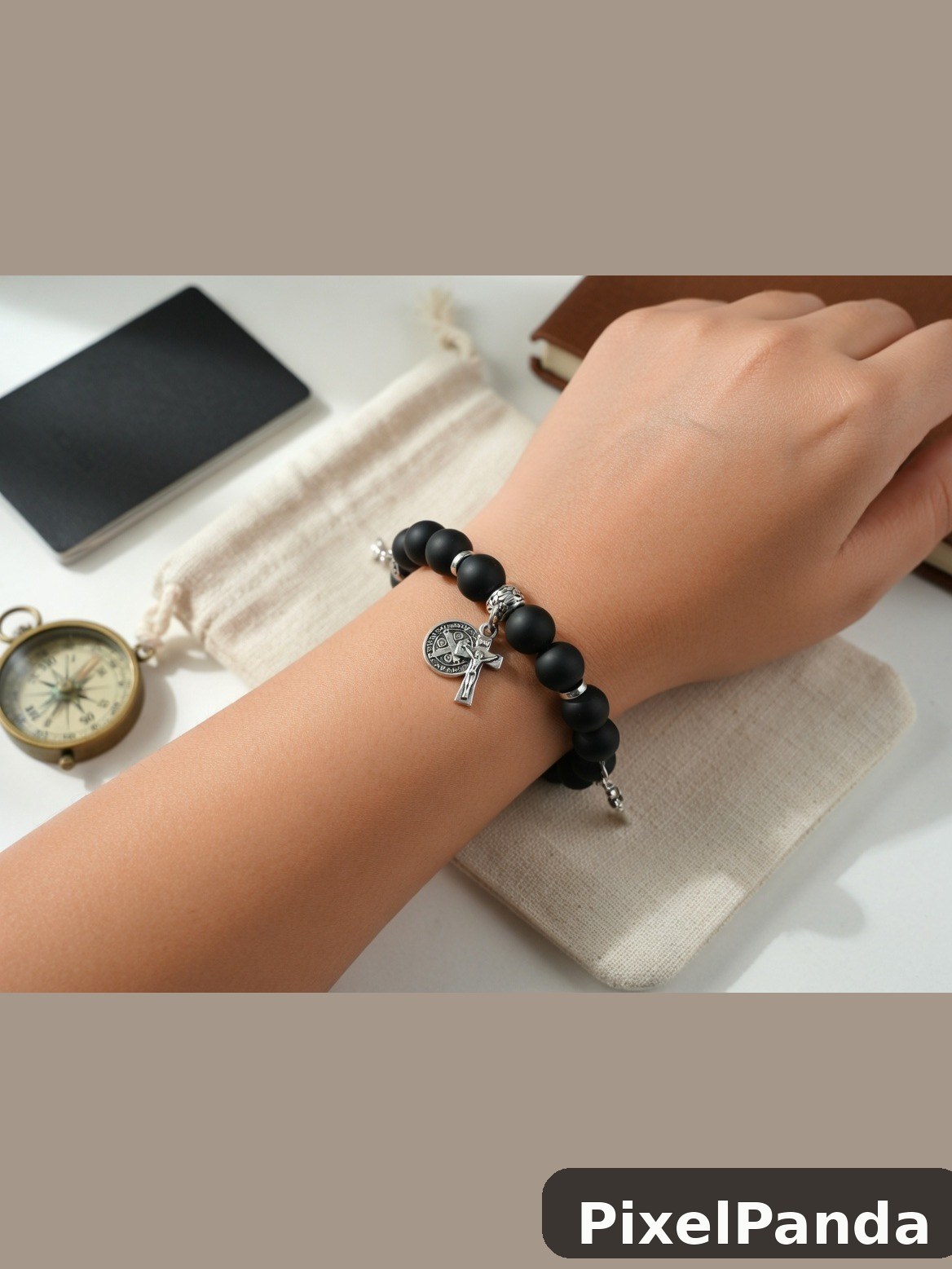 Black beaded bracelet with silver cross charm on wrist