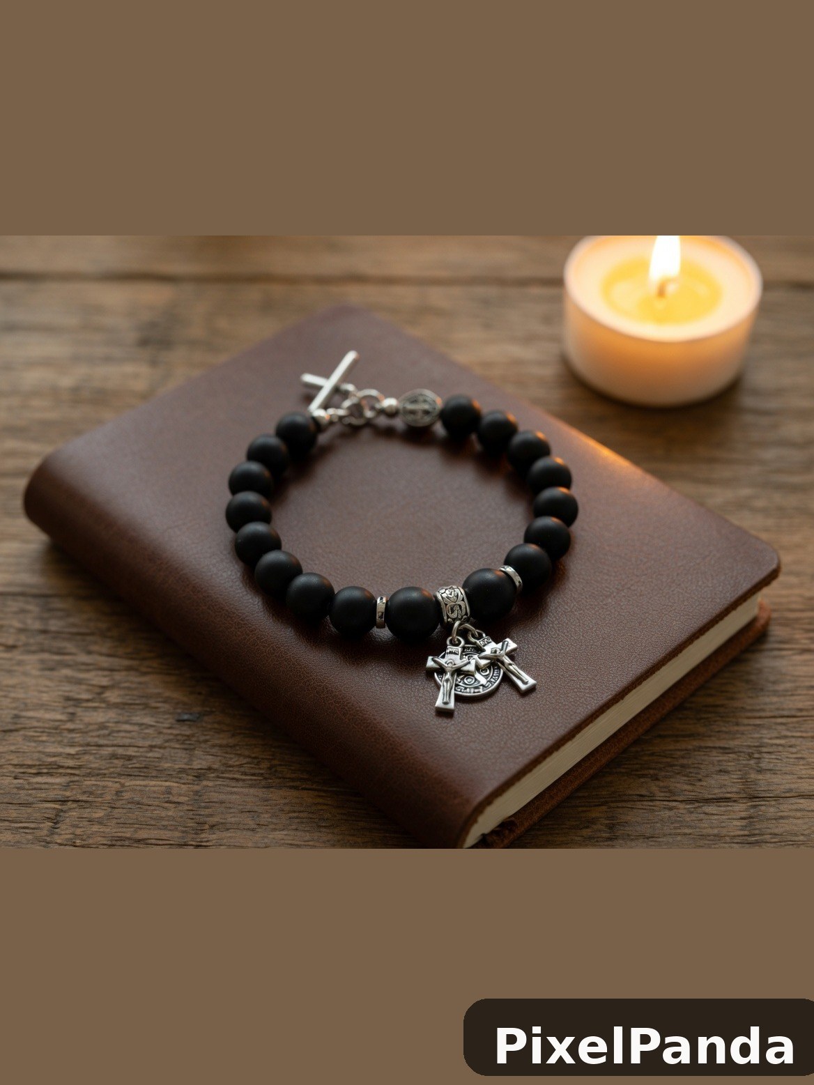 Black beaded bracelet with silver cross charm on brown leather journal