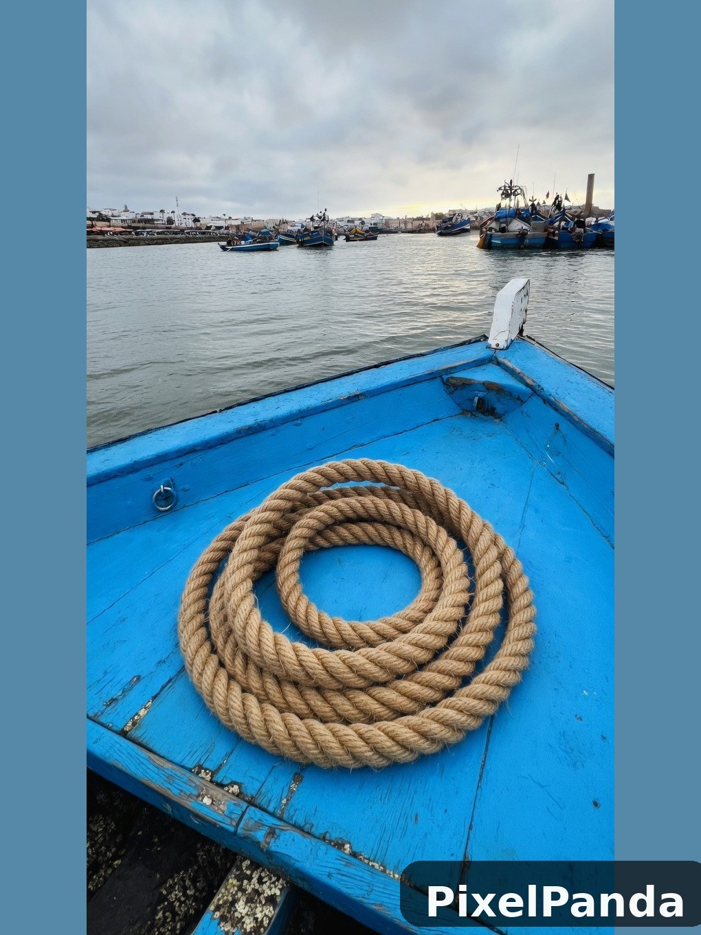 Coiled rope on bright blue fishing boat deck with harbor