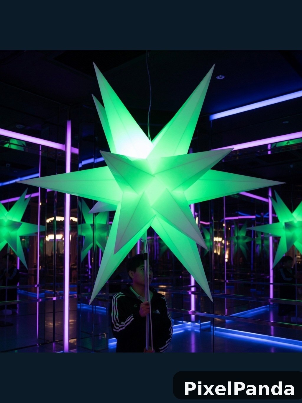 Person standing beneath glowing green star sculpture at night