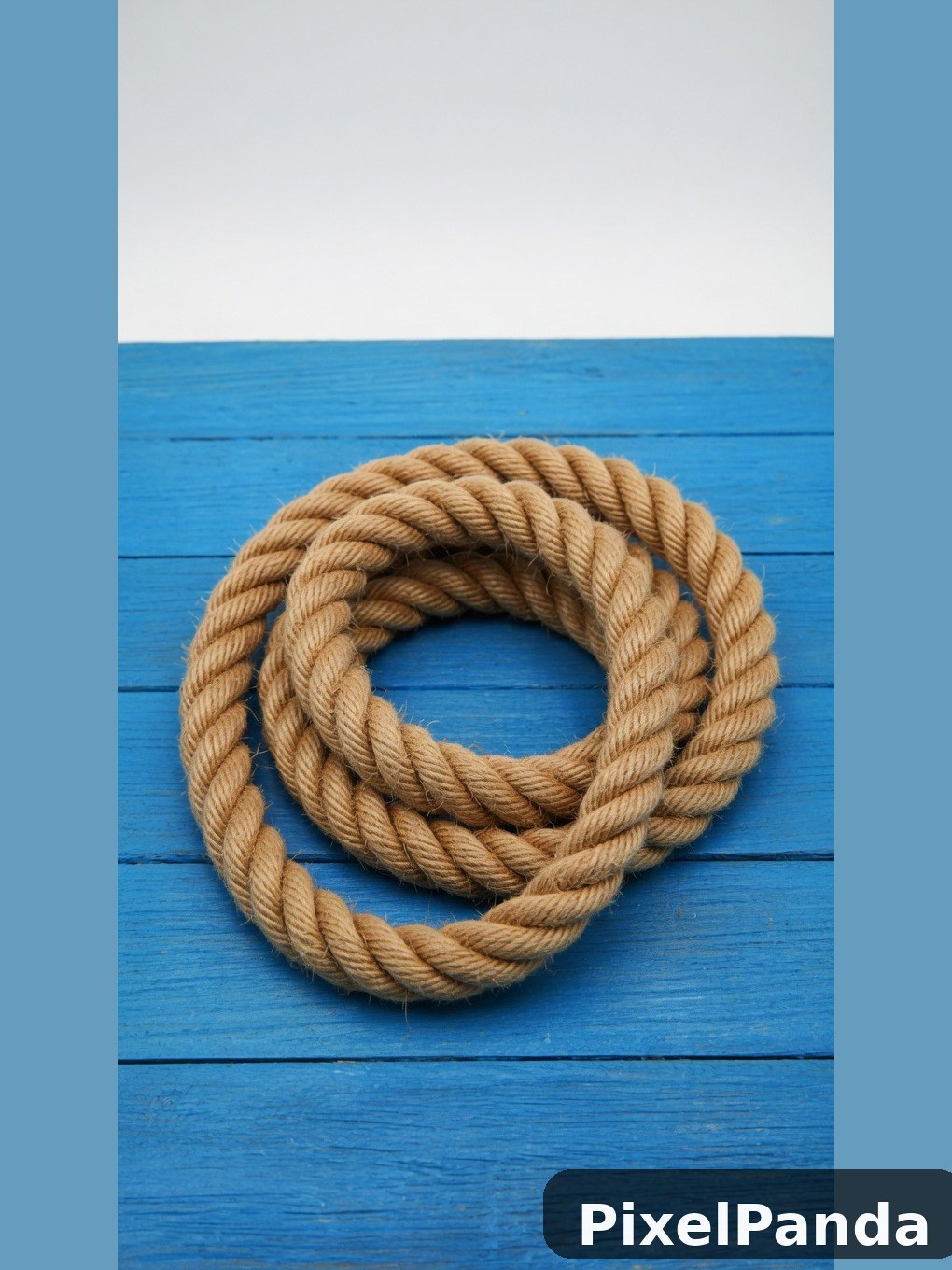 Coiled natural rope on bright blue wooden planks