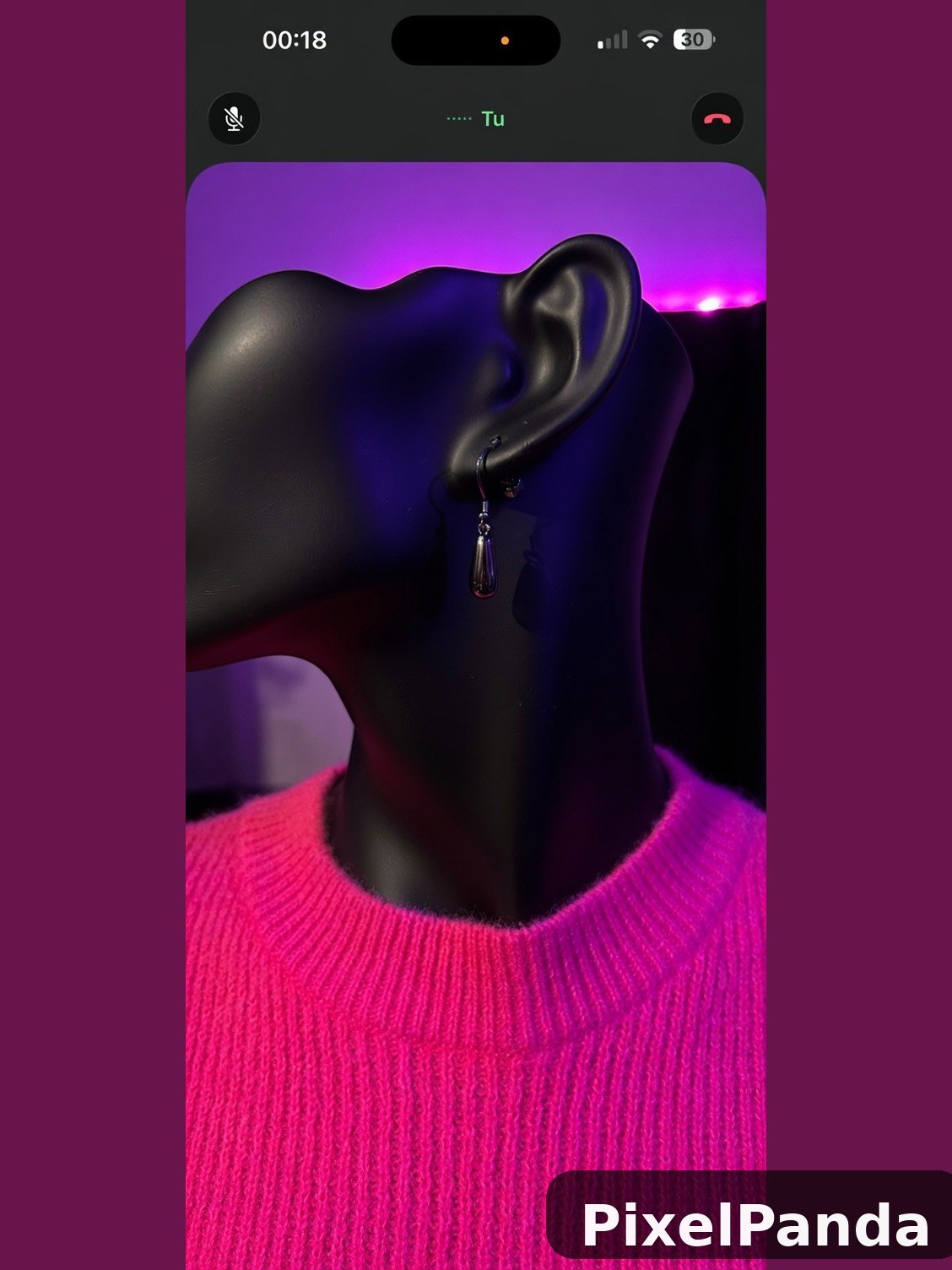 Person with dark skin wearing bright pink sweater and drop earrings