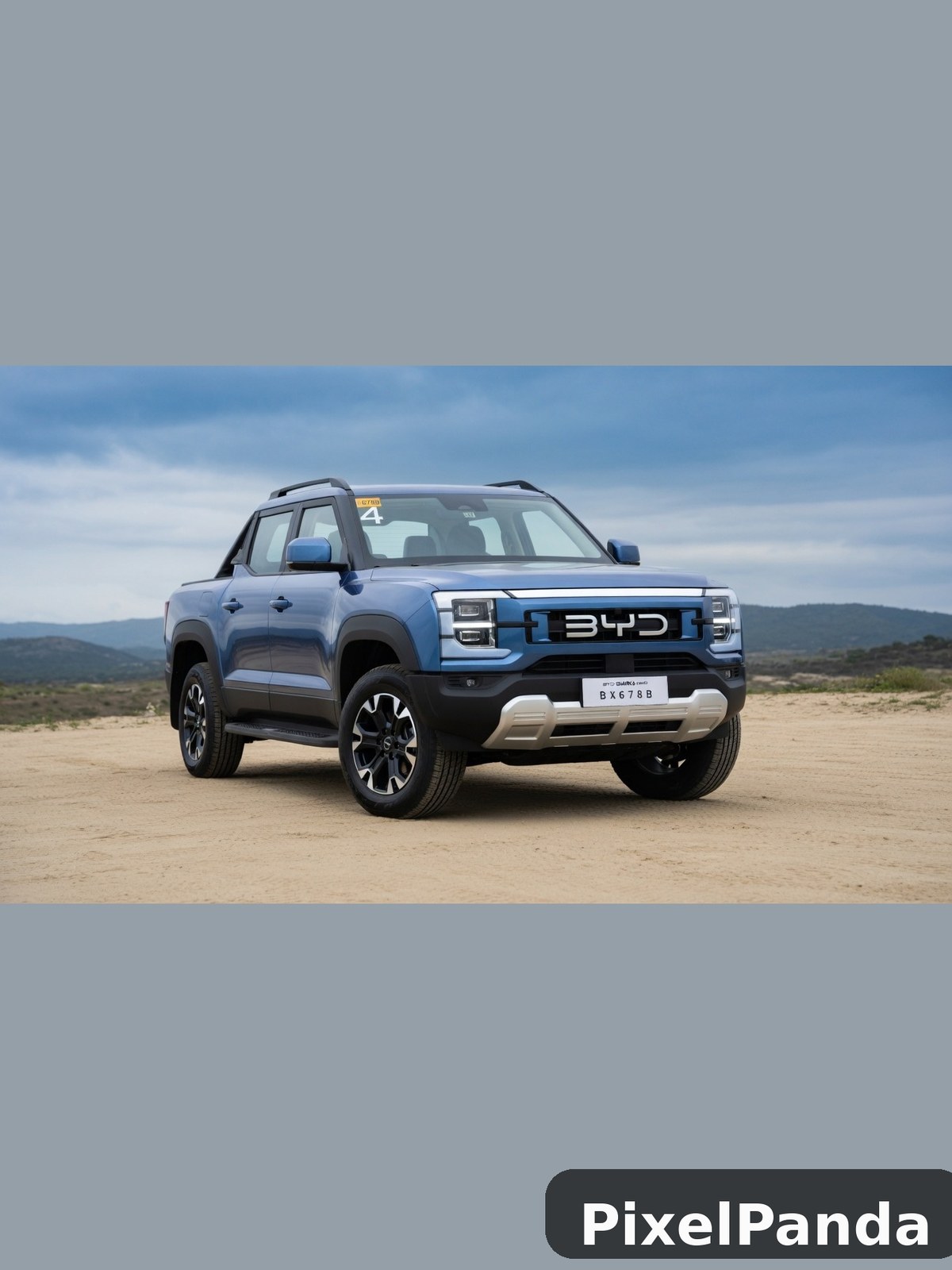 Blue pickup truck parked on desert sand with mountains behind