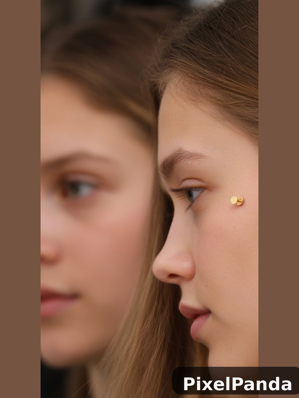Person in profile with small gold ear studs and brown hair
