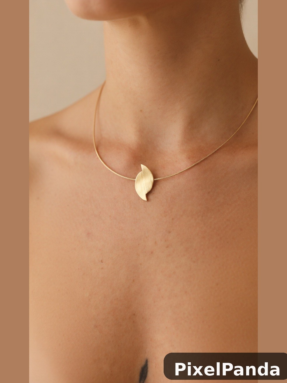 Person wearing delicate gold chain necklace with leaf pendant