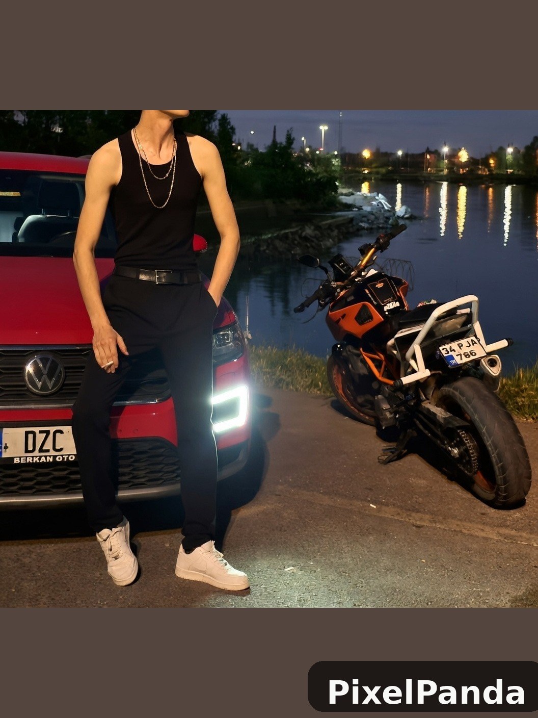 Person in black tank top and white sneakers standing by red truck at dusk
