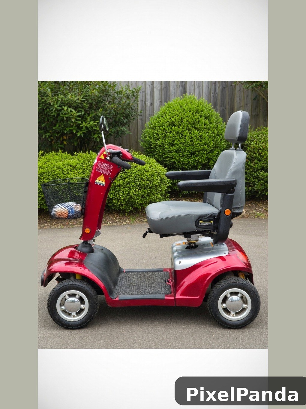 Red four-wheel mobility scooter parked in garden setting