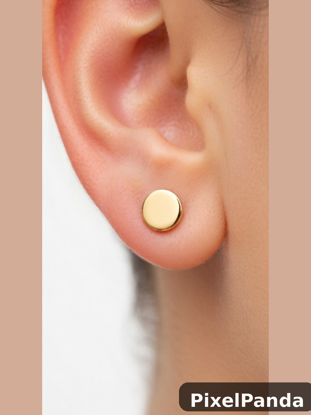 Small gold and cream enamel stud earring on pierced earlobe