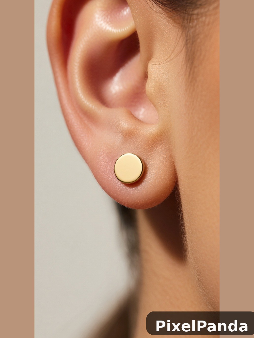 Small gold disc earring on person's earlobe