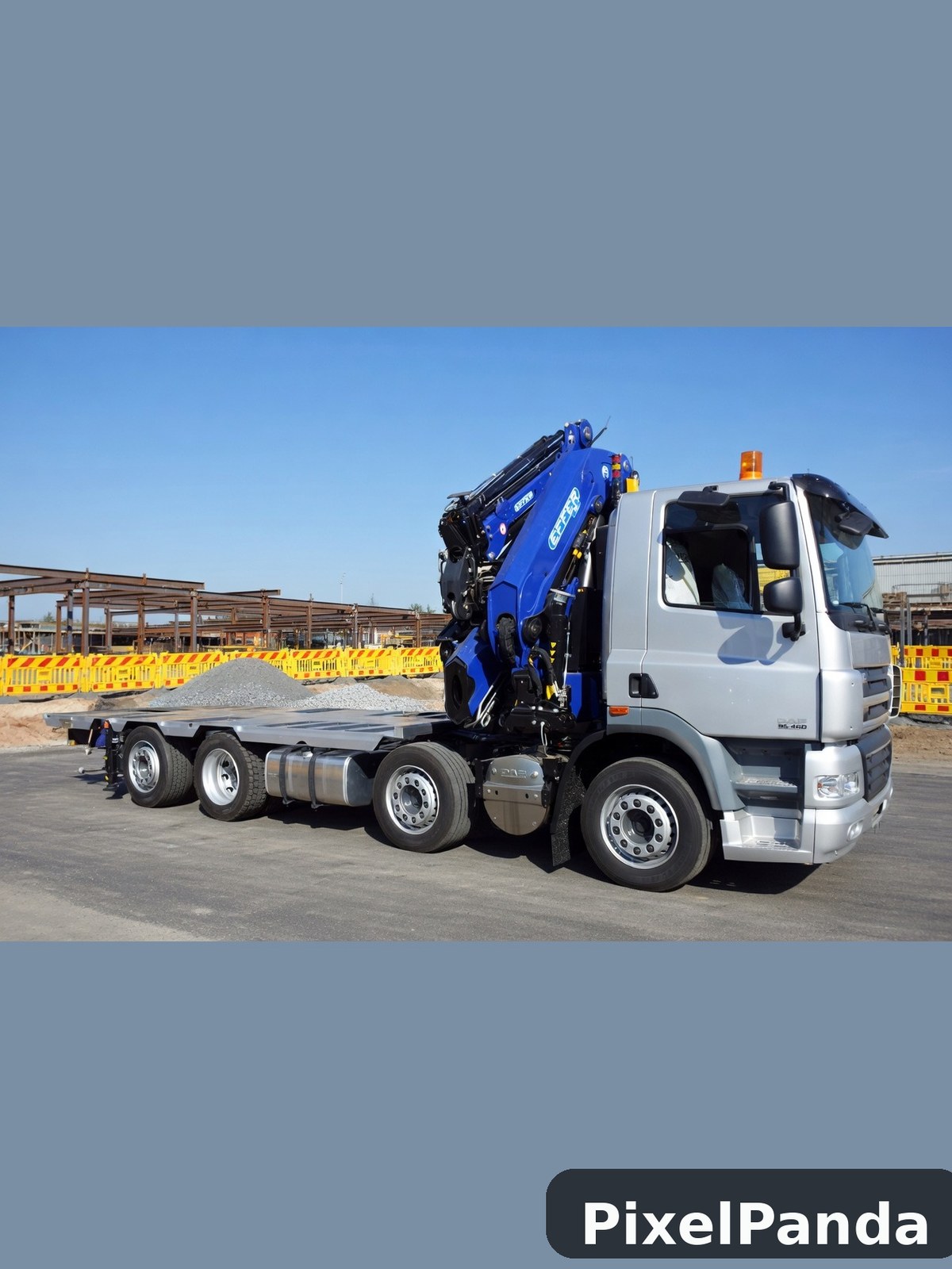 White and blue truck with hydraulic crane arm in construction yard