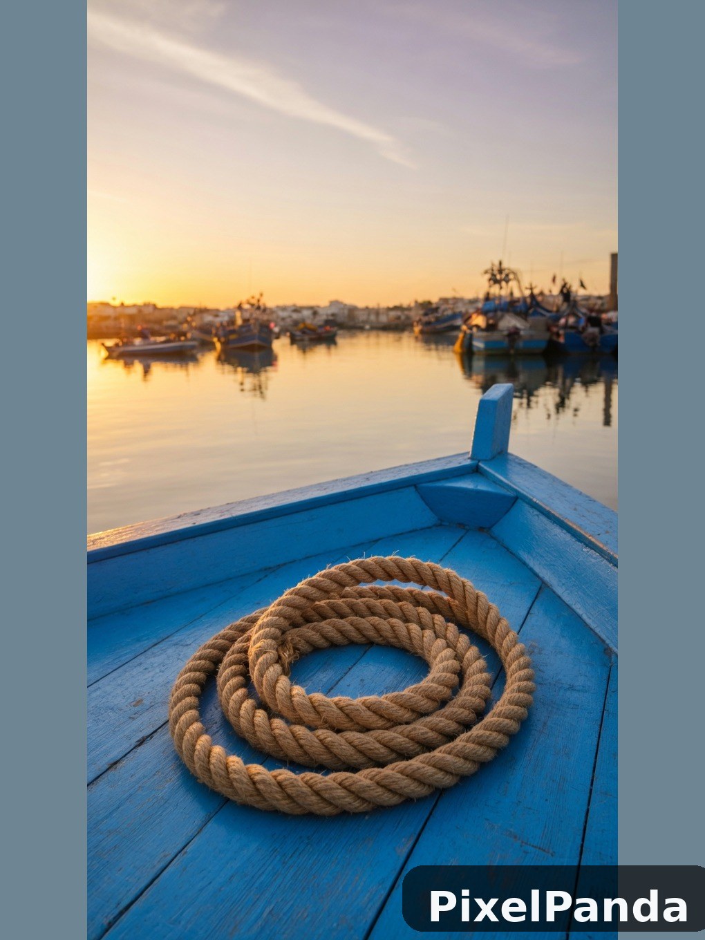 Coiled rope on blue fishing boat at sunrise harbor