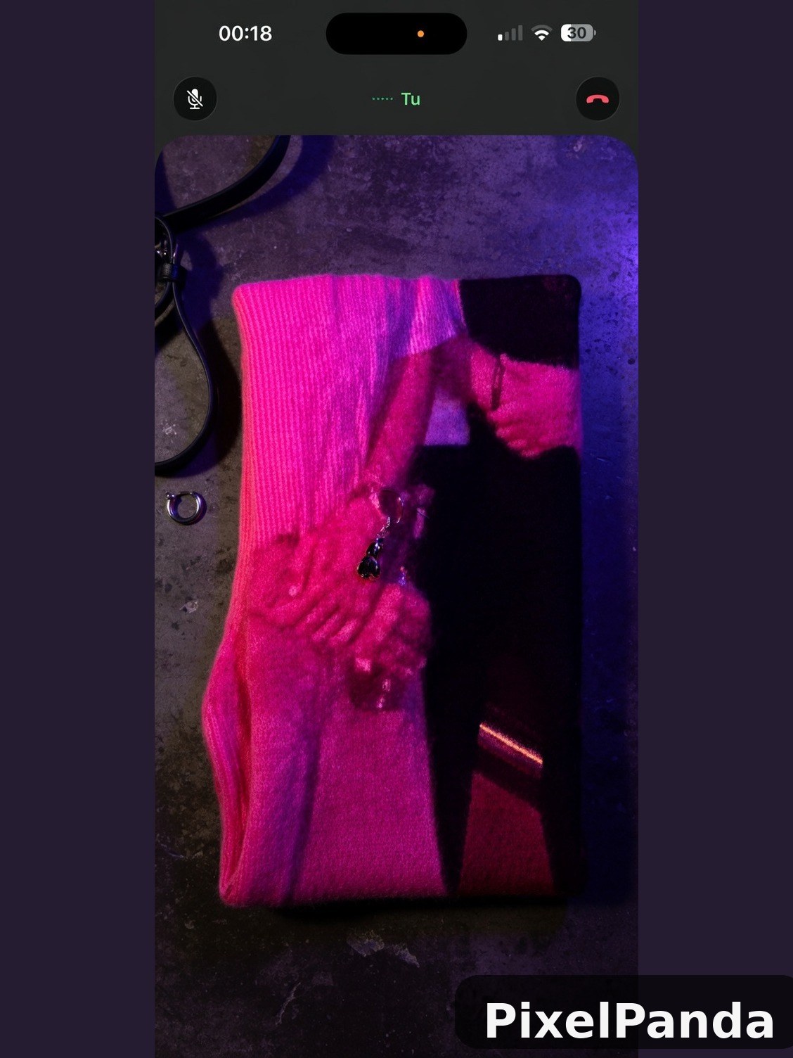 Person in bright pink ribbed sweater under neon purple lighting