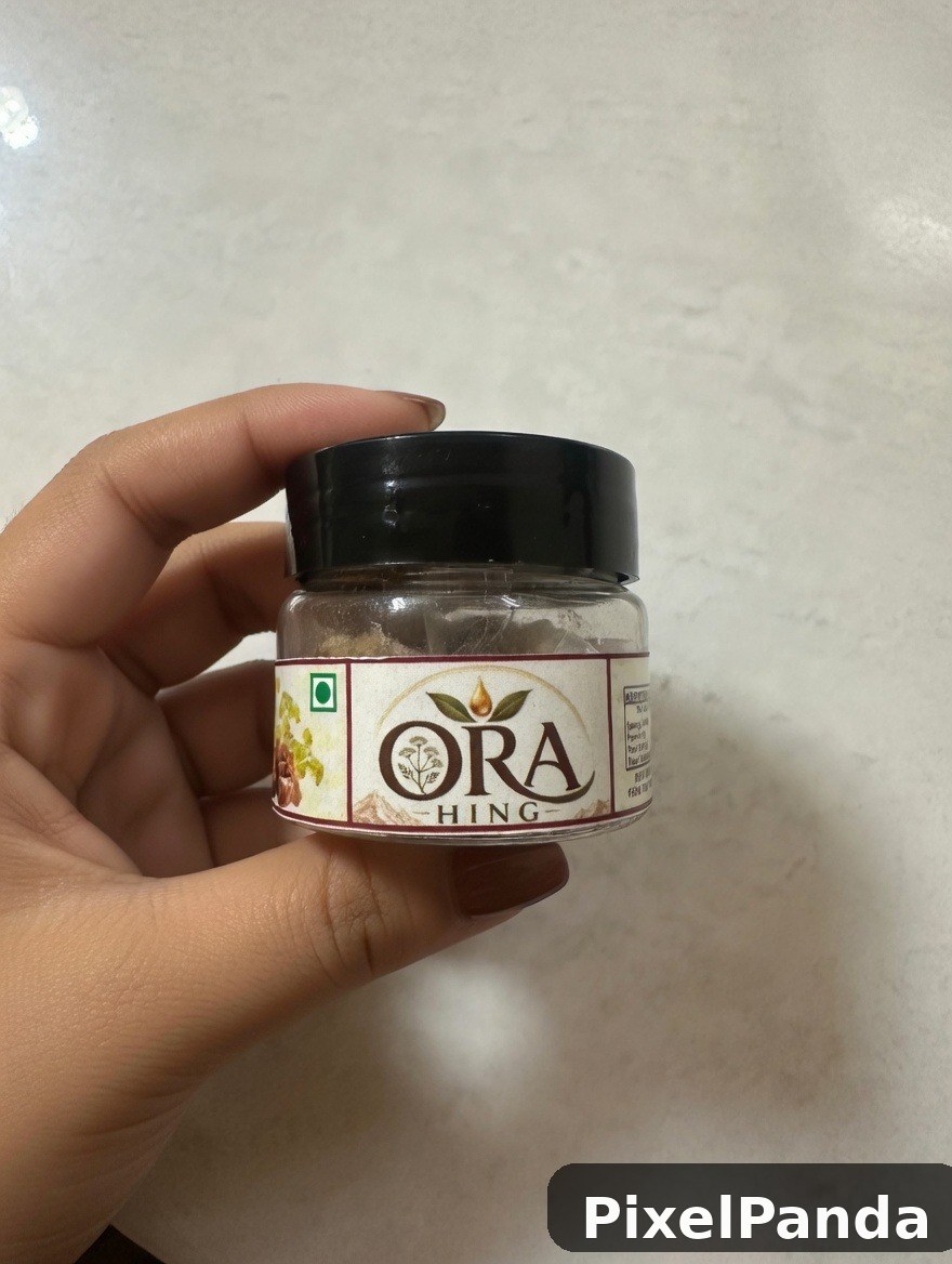 Hand holding small glass jar with black cap and botanical label
