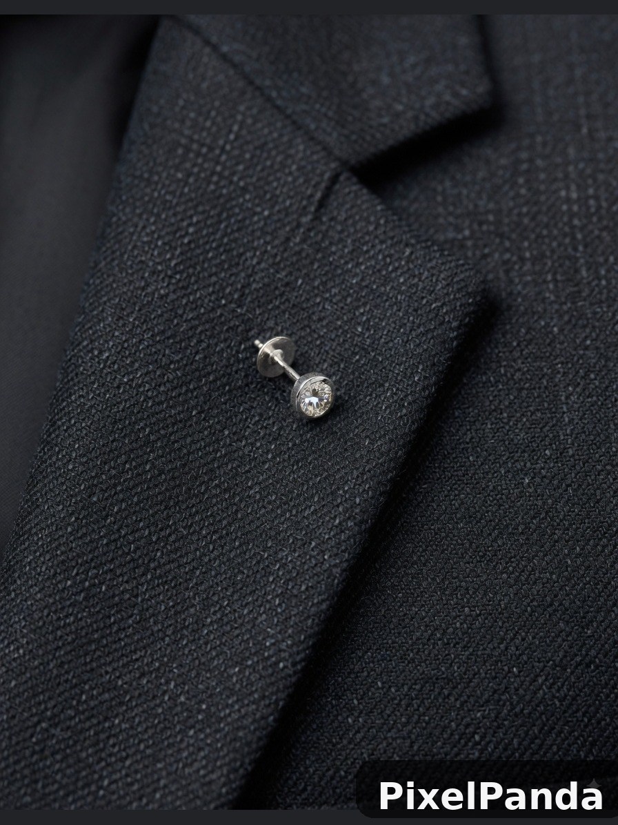Silver stud earring on dark textured fabric