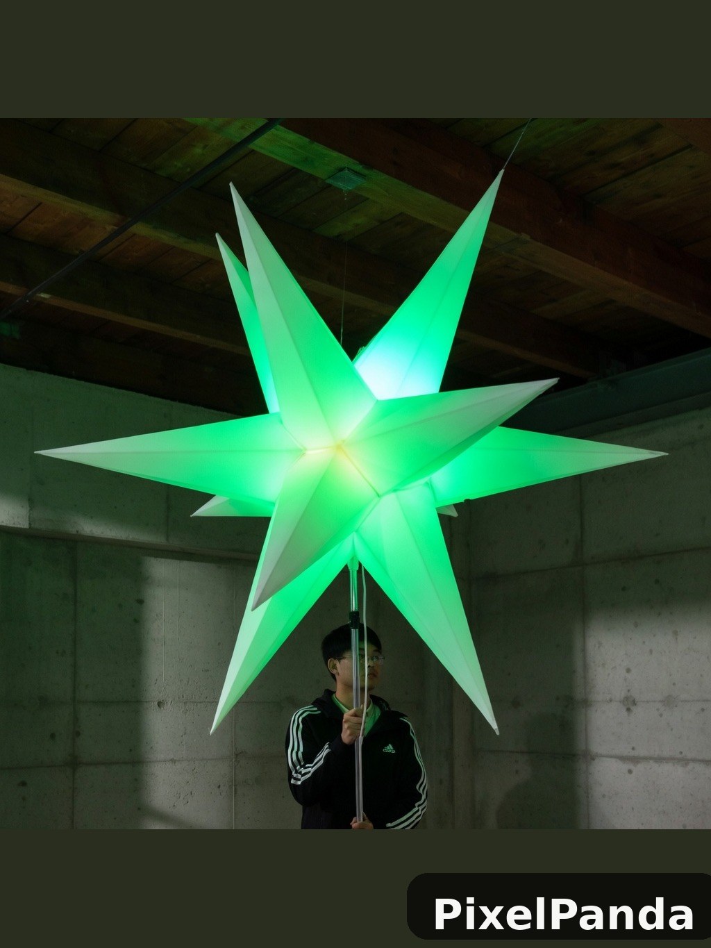Person holding glowing green star sculpture in concrete space