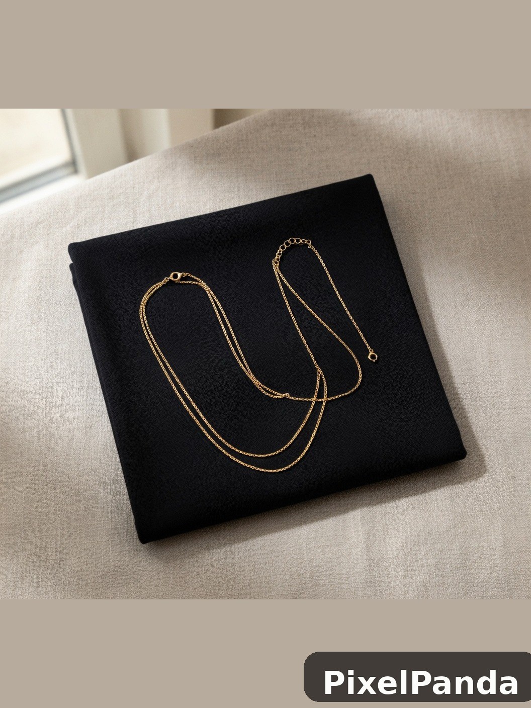 Pair of delicate gold chain necklaces on black fabric